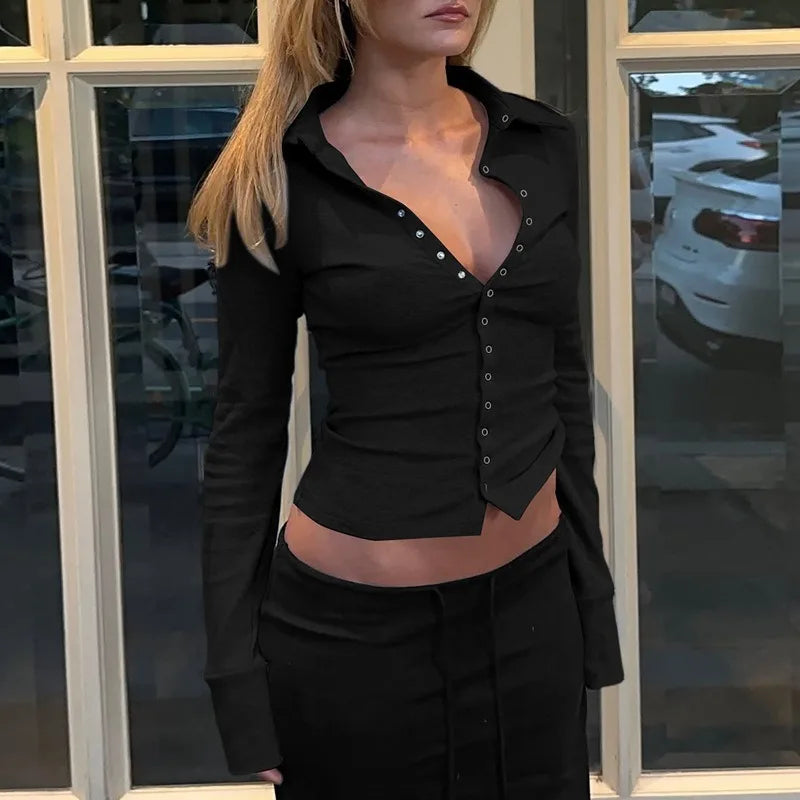 Person wearing a black button-up shirt with a low neckline in front of a window.