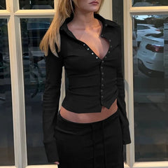 Person wearing a black button-up shirt with a low neckline in front of a window.