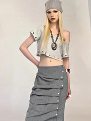 Person wearing a gray outfit with a long skirt and crop top on a plain background
