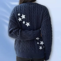 Person wearing a dark blue sweater with star patterns on a light blue background