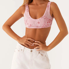 Person wearing a pink floral crop top and white pants on a light background