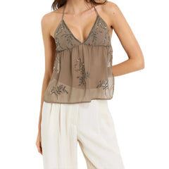 Woman wearing a beige embroidered top and white pants 