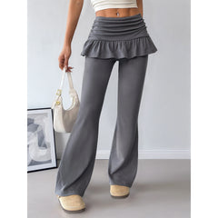 Person wearing gray flared pants with a ruffled top in an indoor setting