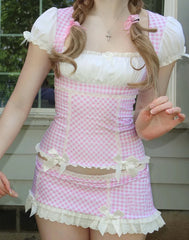 Person wearing a pink and white checkered dress with ruffles outdoors.