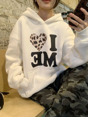Person wearing a white hoodie with 'I ❤️ ME' text, sitting indoors.