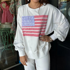Person wearing a white sweatshirt with an American flag design in a store setting.
