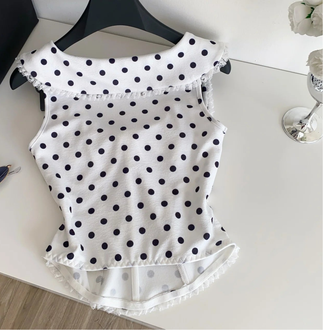 White polka dot top on a hanger 