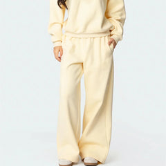 Person wearing a cream-colored tracksuit on a light gray background
