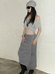 Person wearing a gray crop top and skirt with a white wall background