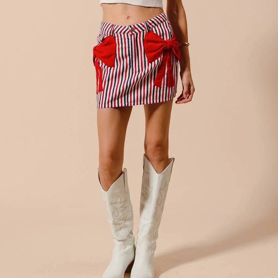 Person wearing a red and white striped skirt with bows and white cowboy boots on a beige background