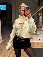 Person wearing a white sweater with a cut-out design and black skirt in a room.