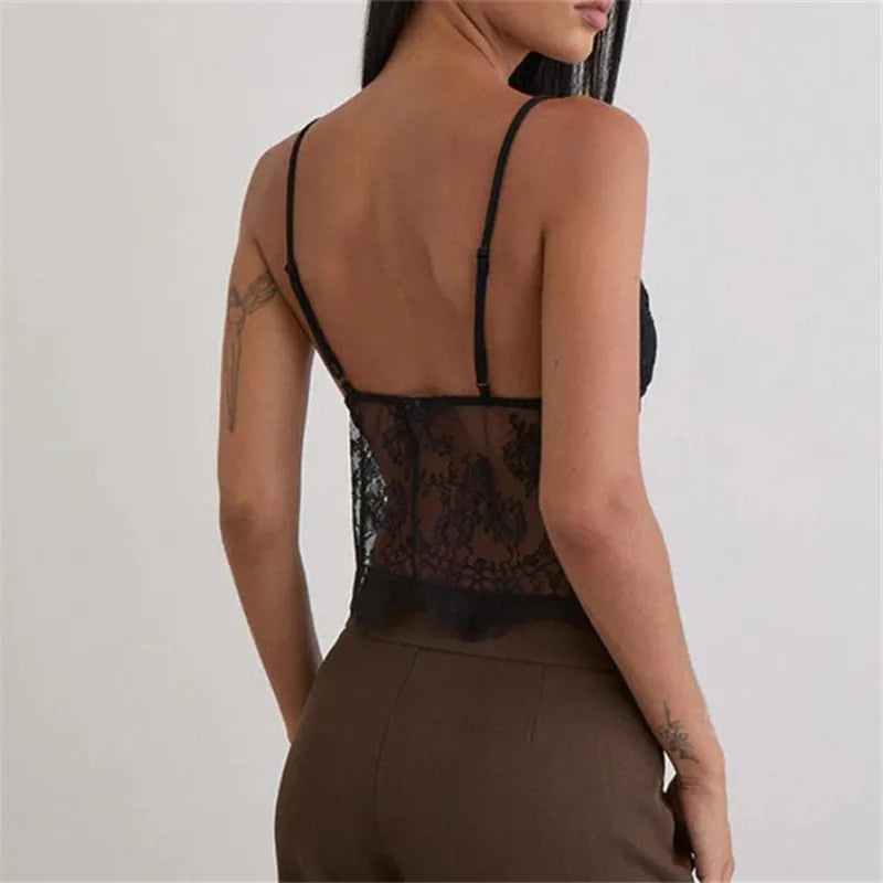 Person wearing a black lace top with sheer design on a plain background