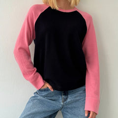 Person wearing a black and pink long-sleeve shirt with blue jeans 