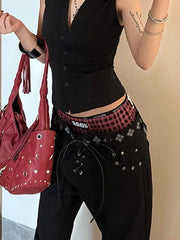 Person wearing a black sleeveless top and black pants with a red studded handbag.