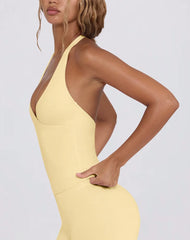 Woman wearing a yellow dress with a halter neck design on a plain background