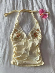 Cream-colored lace top with floral embroidery on a white fabric background