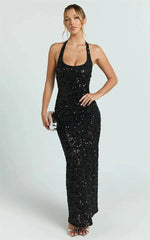 Woman posing in a black sequin halter maxi dress with one hand on her hip.