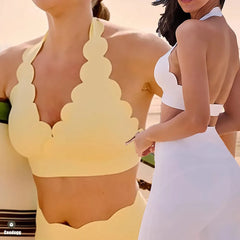Two women wearing bikini tops with unique cut-out designs on a beach.