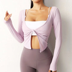 Person wearing a light purple long-sleeve top with a knot detail over a white sports bra 