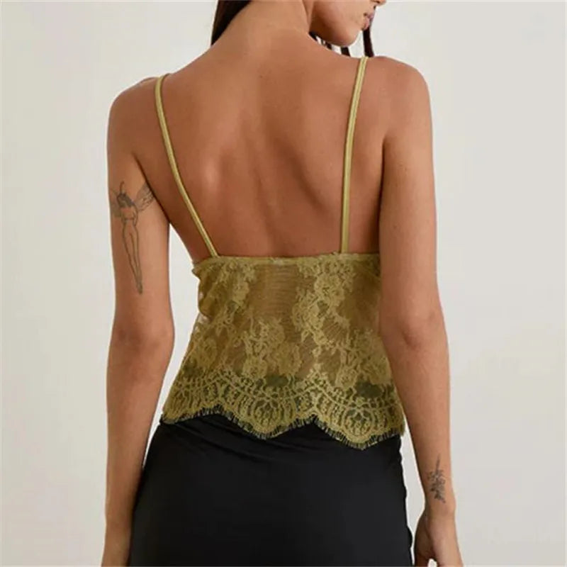 Woman wearing a green lace top with thin straps on a plain background