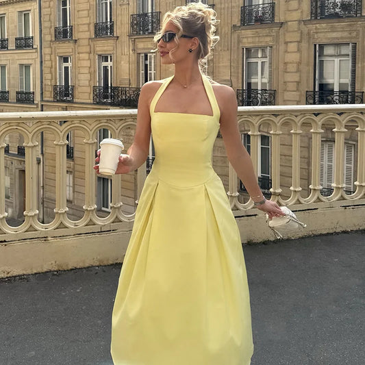 Woman in a yellow dress holding a coffee cup in an urban setting