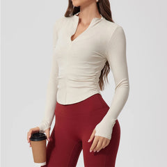 Woman wearing a white long-sleeve top and red leggings holding a coffee cup on a light gray background