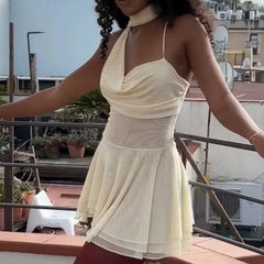 A white mini dress featuring a draped scarf, strappy design, and frill details, shown on model.