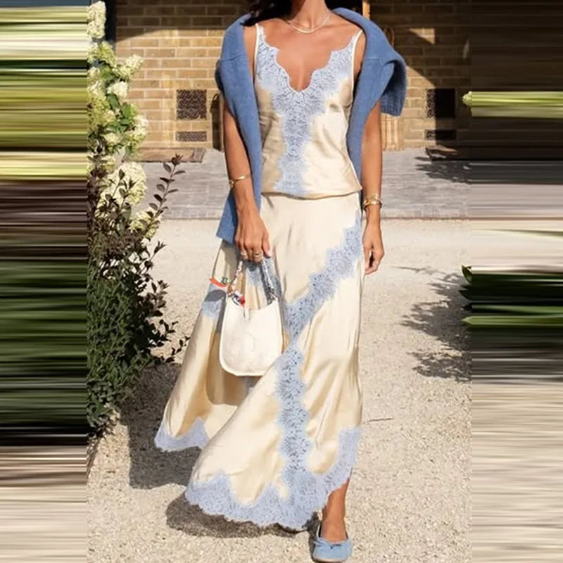Woman wearing a cream dress with blue lace details and a blue cardigan, holding a white handbag.