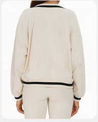 Person wearing a cream-colored outfit with black trim- back view