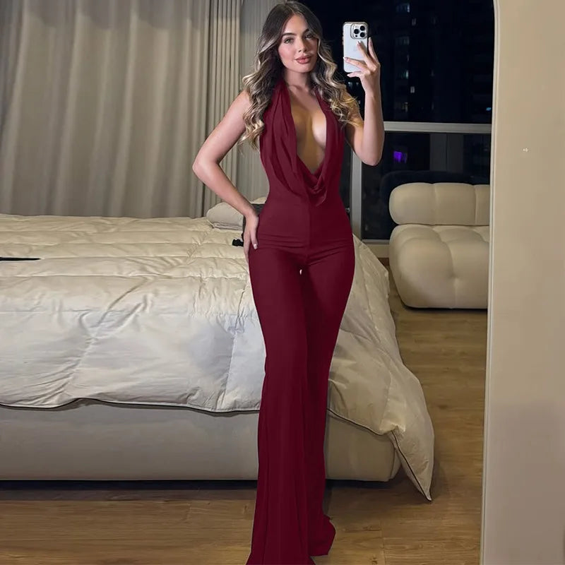Woman taking a mirror selfie wearing a red jumpsuit in a bedroom.