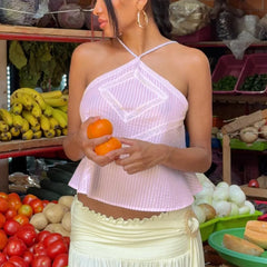 Woman holding oranges in a market setting with fruits and vegetables around