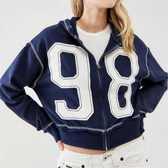 Person wearing a navy blue hoodie with large white numbers '98' on a plain background