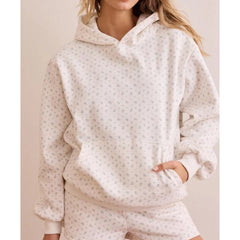 Person wearing a cream-colored hoodie with a subtle pattern on a plain background