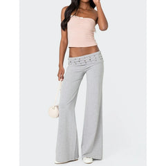 Woman wearing a light pink top and gray flared pants 
