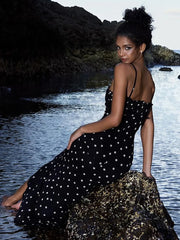 A woman wearing a stylish polka dot midi dress, showing off its flattering fit and playful design.