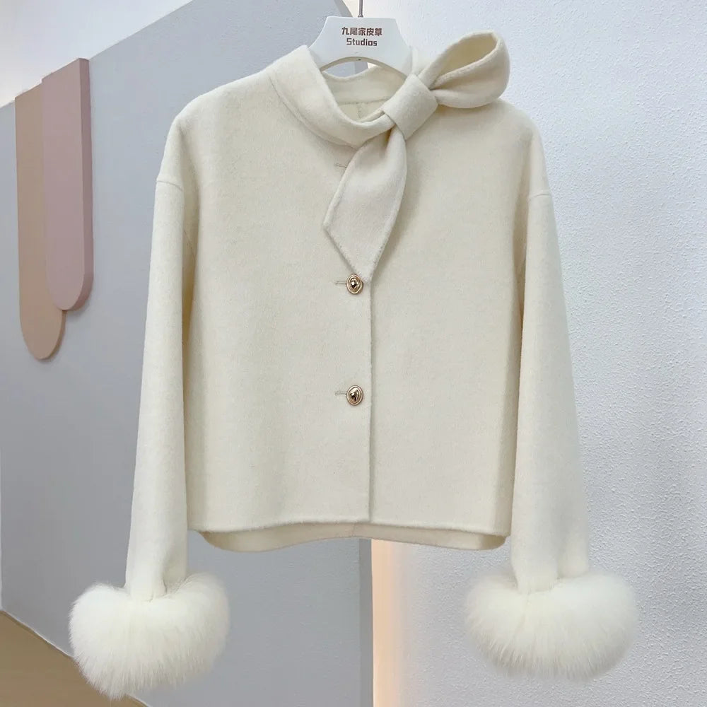 White sweater with a bow and fur cuffs on a gray background