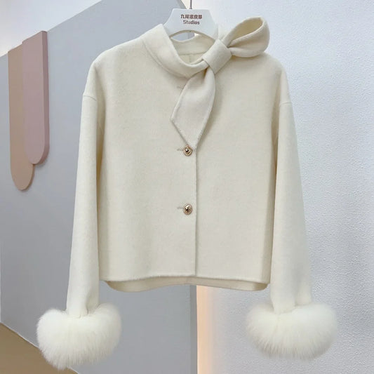 White sweater with a bow and fur cuffs on a gray background