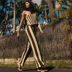 Woman in a striped outfit walking outdoors with palm trees in the background