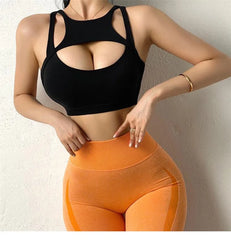 Person wearing a black sports bra and orange leggings against a neutral background