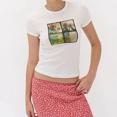 Person wearing a white t-shirt with a colorful graphic design and red floral skirt 