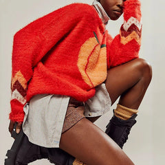 Person wearing a red sweater with a pumpkin design on a neutral background