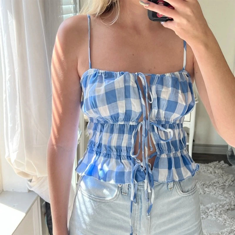 A woman wearing a blue gingham cami top with white jeans, showcasing its versatility and summery style.