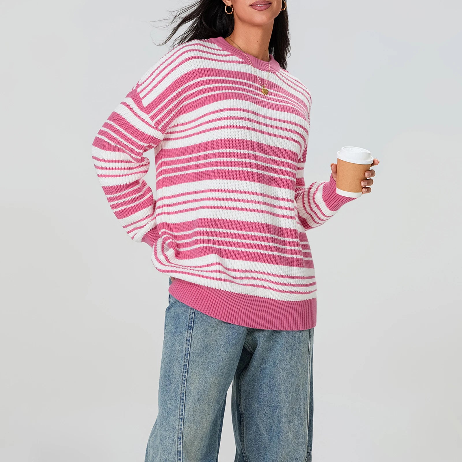 Person wearing a pink and white striped sweater holding a coffee cup against a plain background