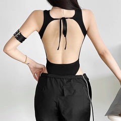 Person wearing a black open-back top and black pants 