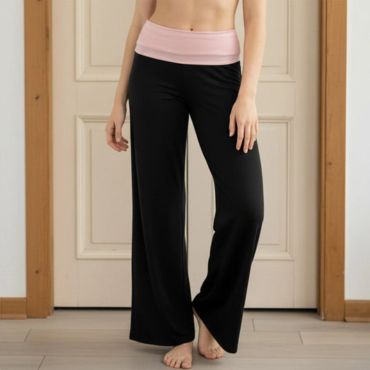 Person wearing black pants with a pink waistband in a room with wooden floors and white walls.
