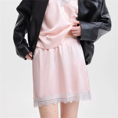 Person wearing a pink satin nightgown with lace hem and a black leather jacket on a white background