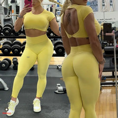 Woman in a yellow athletic outfit taking a mirror selfie in a gym.
