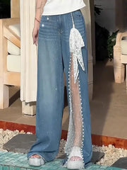 Person wearing blue jeans with a sheer white lace panel on a stone surface.