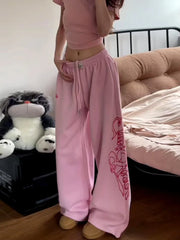 Person wearing pink sweatpants with a design in a bedroom setting