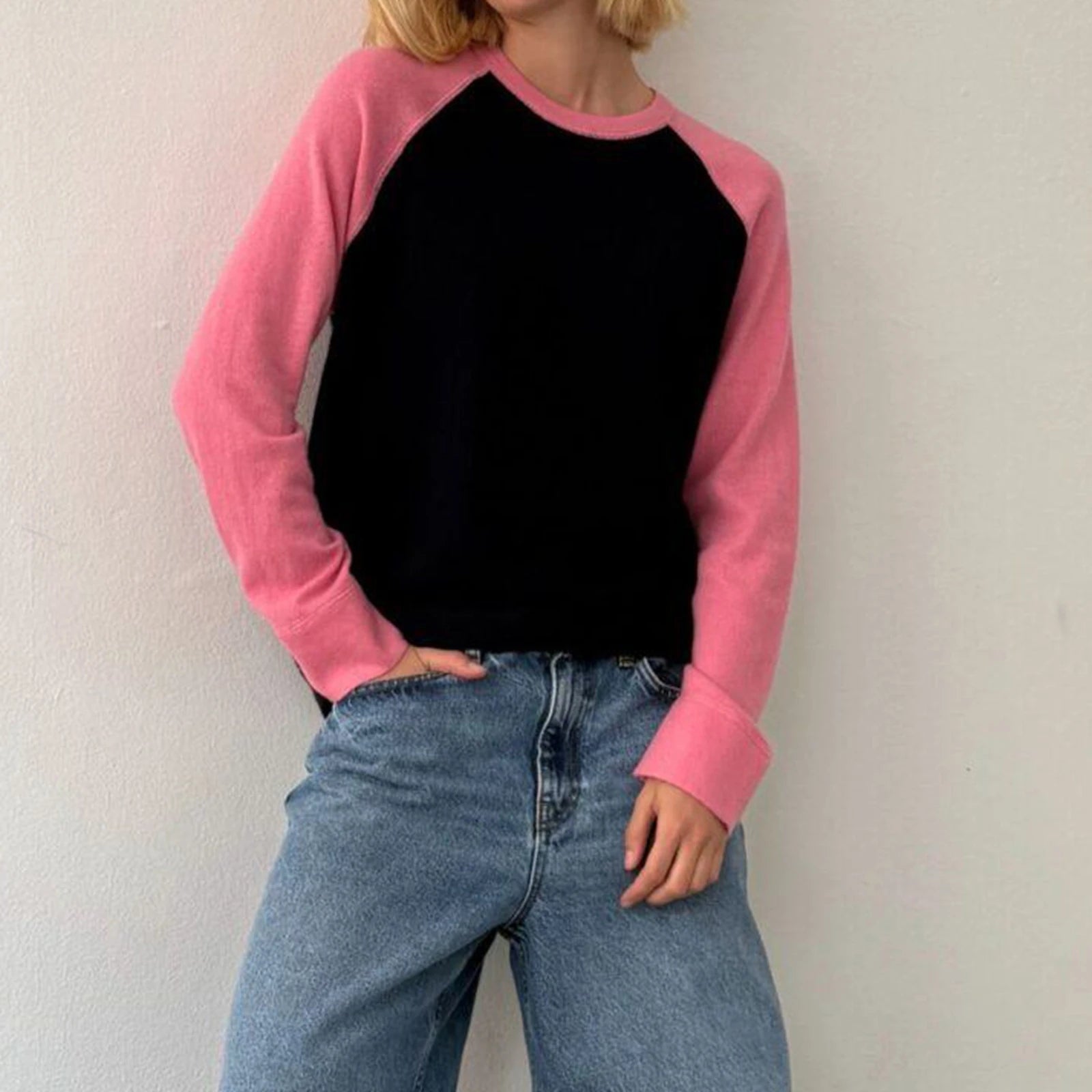 Person wearing a black and pink long-sleeve shirt with blue jeans 